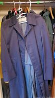 Purple button-up jacket hanging in closet showing front and partial lining.