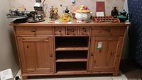 Front view of pine sideboard with two closed cabinets, open shelving center, and items placed on top for scale only