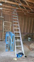 Full view of two-section aluminum extension ladder leaning against rafters