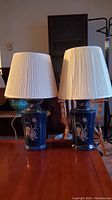 Pair of matching table lamps on wood surface in ambient light.