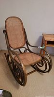 Full view of vintage rocking chair showing bentwood frame and cane seat and backrest.