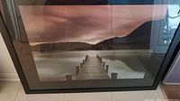 Full view of the framed print showing the dock extending over water with mountainous landscape under a moody sky.