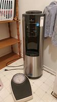 Full view of the Vitapur water dispenser next to the Zenith bathroom scale on the floor.