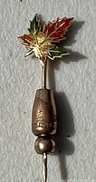 Front view of lapel pin showing the colorful enamel maple leaf and gold stick pin with locking end.