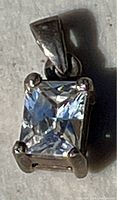 Close-up photo of a square princess-cut clear cubic zirconia set in a sterling silver 925 four-prong pendant.