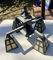 Full view of antique ceiling fixture showing central brass frame with four arms extending to square slag glass shades with black grid design. Lightly painted black on brass surfaces.