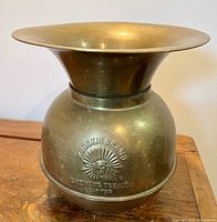Front view of brass spittoon showing flared top and embossed Redskin Brand logo