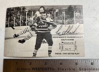Vintage black and white promotional hockey card showing Eddie Shack playfully lifting an opponent. The card features Eddie Shack's signature on the front, his Vaughan Valley Golf Course map, and is measured with a ruler for scale.