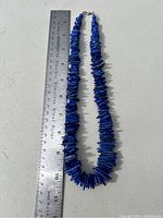 Full length view of the lapis lazuli stone necklace laying flat next to a 12-inch ruler for scale.