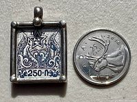 Front view of the square sterling silver pendant with Soviet hammer and sickle motif next to a Canadian 25 cent coin for size comparison.