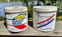 Front view of two Daily Mail branded tobacco tins with original printed labels showing vintage branding and condition.
