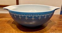 Side view of the blue Pyrex mixing bowl showing the white decorative pattern around the exterior and the bowl's shape including a pouring spout.