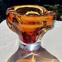 Side angled view of amber glass ashtray showing thickness and color variation in sunlight.