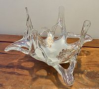 Clear Murano glass centrepiece bowl with abstract organic shape and upward curved points, placed on wooden surface.