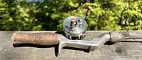 Close-up image of the fishing rod grip with attached reel showing wooden handle and metal reel body.