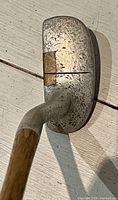 Side view of putter head showing wear and a vertical groove on the striking face.