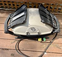 Top view of the Weber portable gas BBQ grill, showing the beige lid with black side vents closed and the attached gas hose coiled in front.