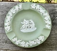 Top view of the green Wedgwood ashtray showing white decorative grapevine motifs and central animal and cherub relief.