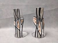 Both glass sculptures from front view showing black abstract linear designs with brown-orange and white geometric shapes
