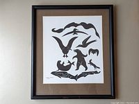 Full view of framed print showing black and white stylized animals in a black frame with brown matting.
