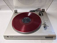 Front angle view of Dual CS 514 turntable with red vinyl on platter, showing wrapped cables and clear dust cover.