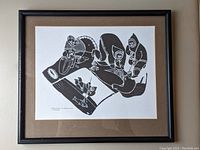Photo of framed black and white Inuit print titled 'Family at Work' by Juanisialuk, showing family members engaged in traditional activities.