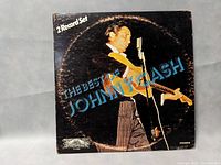 Front cover of the album showing Johnny Cash performing with a guitar, indicating it's a two-record set titled 'The Best of Johnny Cash'.