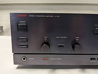 Close-up of front panel controls showing power switch, speaker selectors, tone knobs, headphone jack and operation indicator.