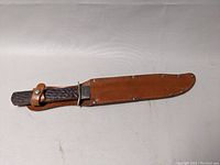 Photo of complete Bowie knife sheathed in thick leather