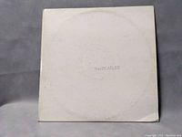 Front of The Beatles White Album vinyl showing plain white cover with subtle text and wear marks.