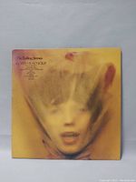 Front cover of The Rolling Stones "Goats Head Soup" vinyl record album showing blurred face artwork on yellow-orange background with title and artist name.