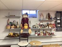 Wide shelf view of the lot showing Halloween scarecrow figure, Easter baskets, assorted seasonal figurines, small ornaments and decorations on multiple shelves