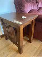Side view of one wooden end table showing flat top and vertical slat sides near couch
