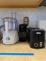Three kitchen appliances on countertop: Hamilton Beach food processor, Black and Decker can opener, black toaster