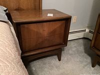 Front left angle view showing two drawers, tapered legs, and overall wood finish.