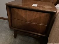 Front view of walnut-finish two-drawer nightstand on carpet.
