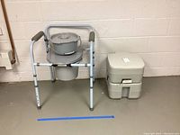Photo showing the portable commode with aluminum frame, padded armrests, and removable bucket on the seat. Next to it is a separate portable toilet seat unit.