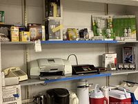 Wide view of shelf showing vintage telephone, HP officejet printer, various light bulbs and electronic devices on top shelf, and kitchen appliances below.