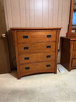 Front view of the Rivers Edge solid wood dresser showing four drawers and metal drop handles with a slightly curved bottom drawer.