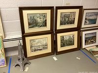 Photo of four framed Paris prints and a metal Eiffel Tower statue on the floor beside them.
