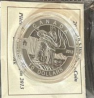 Front view of the 2013 Canada $10 Silver Inukshuk coin in protective casing with certificate behind it.