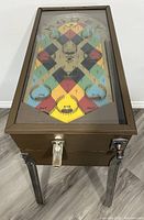 Angled front view showing brown metal cabinet, coin slot, payout lever, spring plunger and metal legs