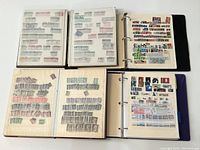 Four 3-ring binders open to display stock pages filled with assorted world postage stamps.