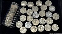 Full roll of roughly 50 Canadian nickels with some laid out showing their reverse sides with beaver design.
