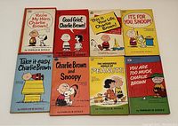 Photo showing full collection of 8 Peanuts paperback books with colorful character covers laid out side-by-side.