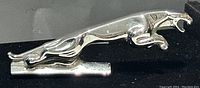 Close-up photo of the chrome Jaguar leaping cat hood ornament, front angle showing detailed features and shiny chrome finish with minor blemishes.
