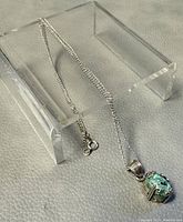 Full view of chain displayed with pendant on clear stand, showing necklace length and-clasp