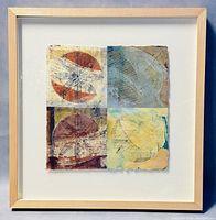 Front view of framed mixed media painting showing four quadrants with abstract organic shapes in various colors on textured Japanese paper, set in a light wood frame.