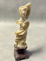 Front angled view of jade figure sculpture on wooden base