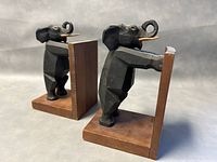 Pair of wooden bookends featuring Art Deco style carved elephants with black paint and wooden bases, shown from an angled front view.